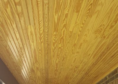 A ceiling with wood planks and a brick wall.