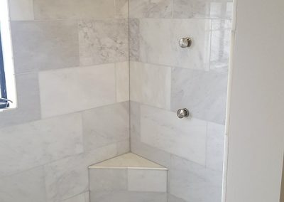 A bathroom with marble tile and white walls.