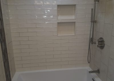 A bathroom with white tile and a tub