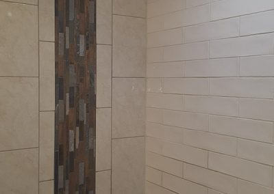 A bathroom with a tiled shower and wood wall.