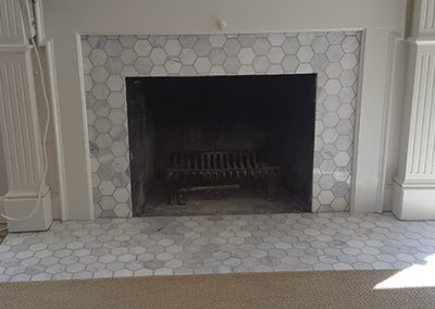 A fireplace with white tile and a black fire place