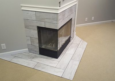 A fireplace with marble tile surround and hearth.