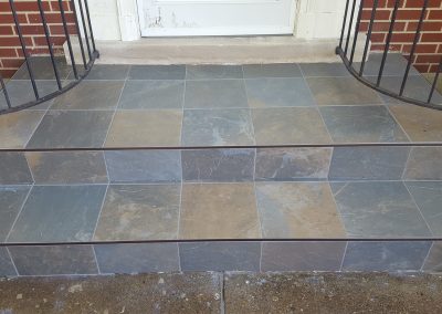 A front porch with steps and tile on the ground.