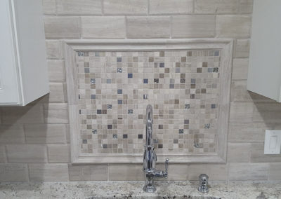 A bathroom with a sink and tiled wall