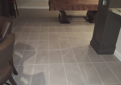 A kitchen floor with tile and wood flooring.