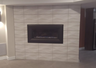 A fireplace with white tile and black trim.