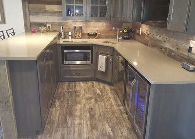 A kitchen with grey cabinets and wood floors.